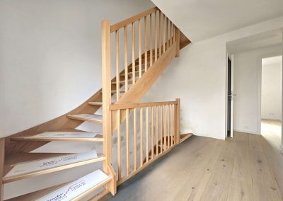 Escalier en bois dans la nouvelle construction Maison Braine-l'Alleud, intérieur lumineux avec parquet clair.