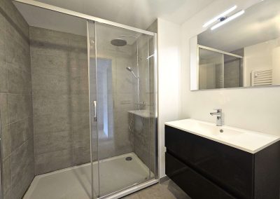 Salle de douche moderne d’une maison à Braine-l’Alleud, avec grande douche vitrée et meuble lavabo.