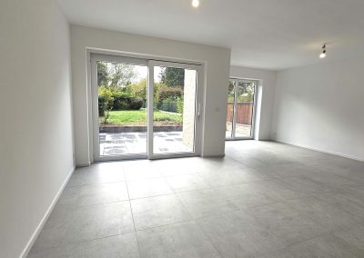 Séjour lumineux d’une maison à Braine-l’Alleud, avec grandes baies vitrées donnant sur le jardin.